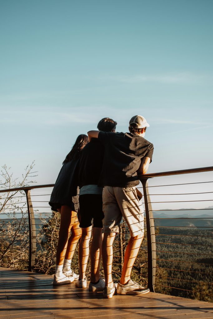 Zwei Männer und eine Frau stehen tagsüber am Geländer