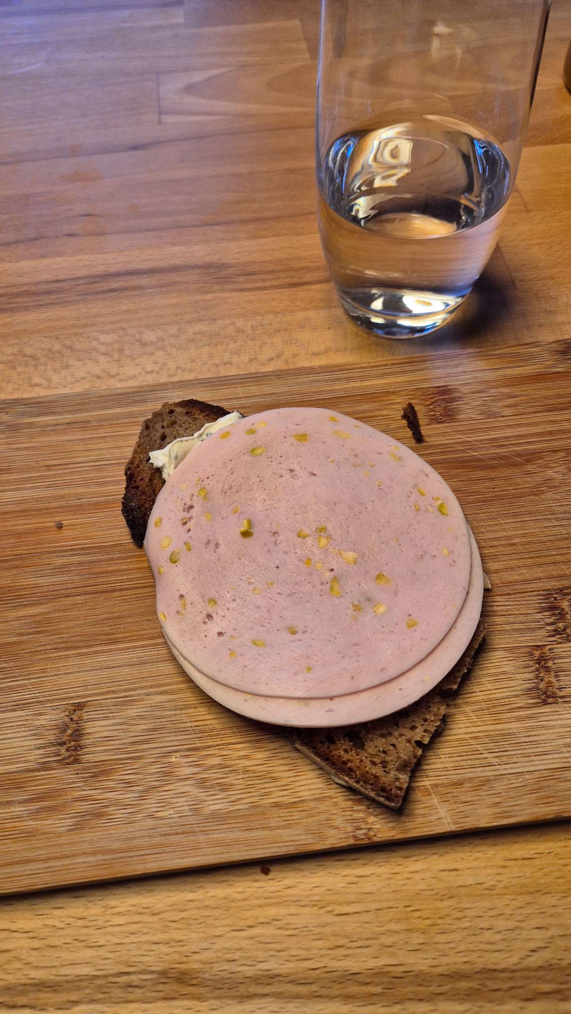 Ein Brot mit Wurst und daneben ein Glas